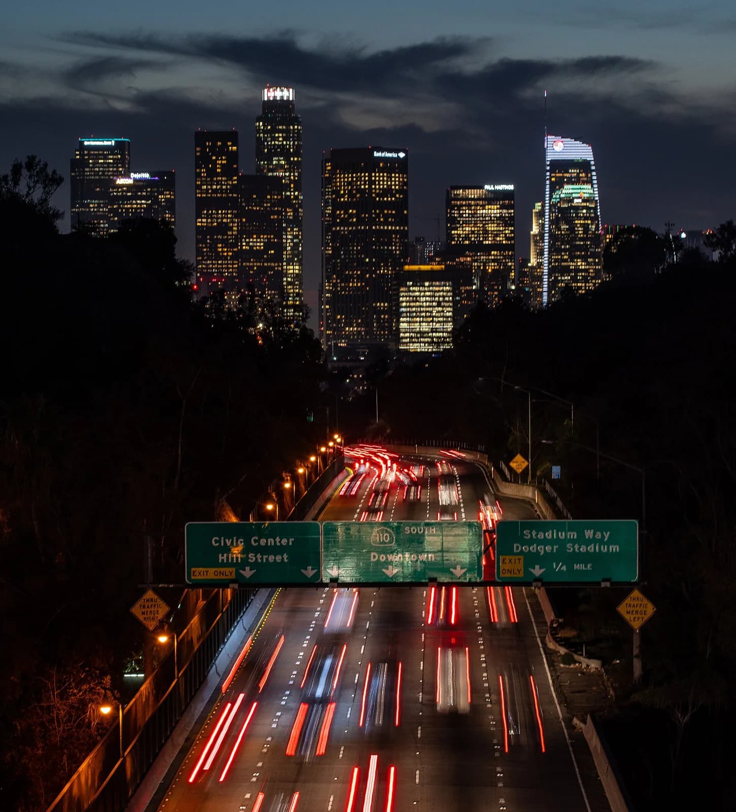Downtown Los Angeles skyline at night as seen from Park Row Bridge in Elysian Park neighborhood, 110 Freeway South, also known as Arroyo Seco Parkway is in view.